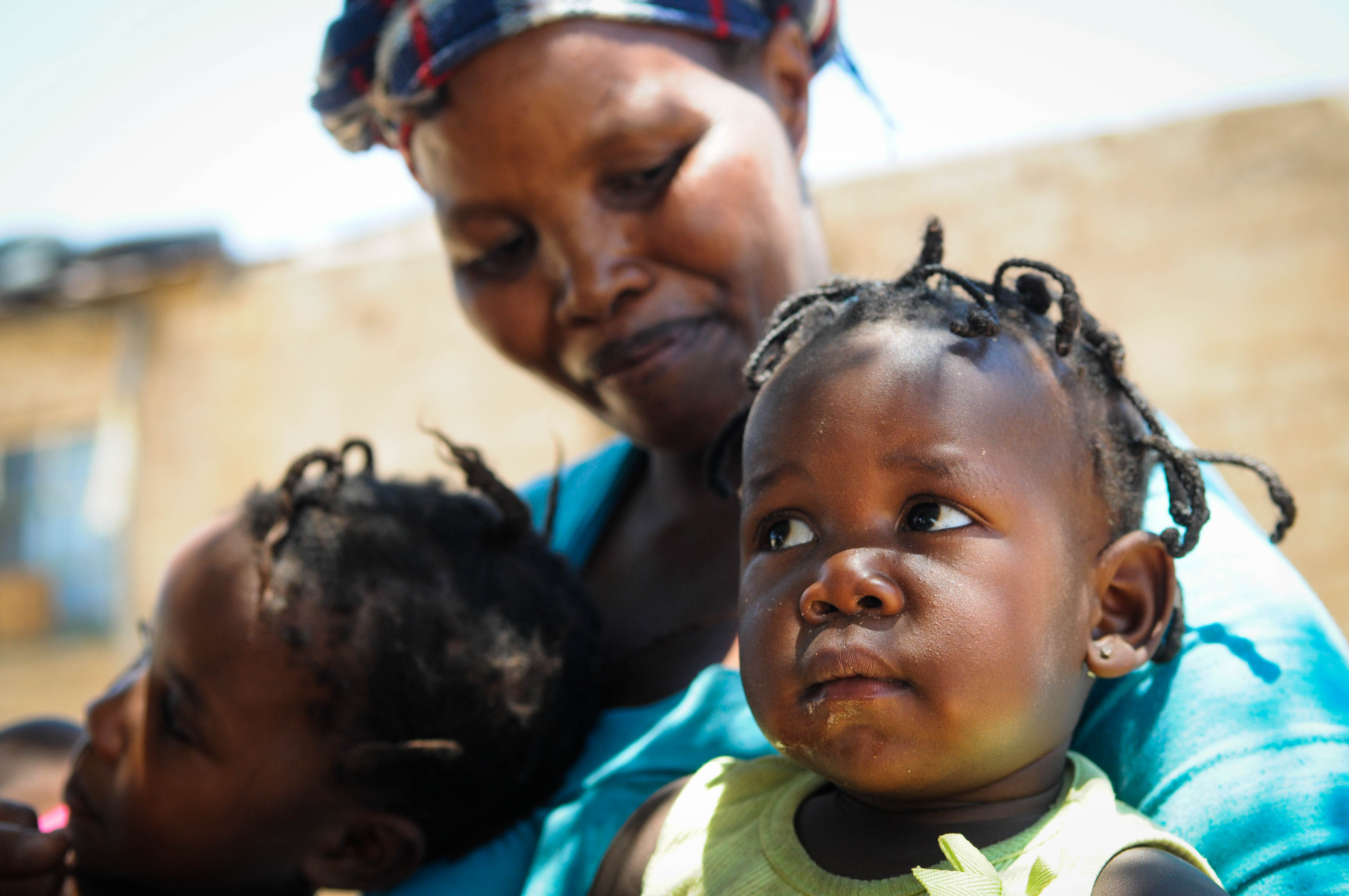 Frau in Afrika mit zwei Kindern. Sie nimmt an einer Selbsthilfegruppe teil