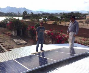 Mitarbeiter beim installieren von Solarpanelen auf einem Dach, was auch das Projekt nachhaltige Landwirtschaft fördert.
